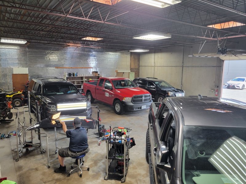 Interior of the PDR Plus Inc shop with several trucks and SUVs in for dent repair
